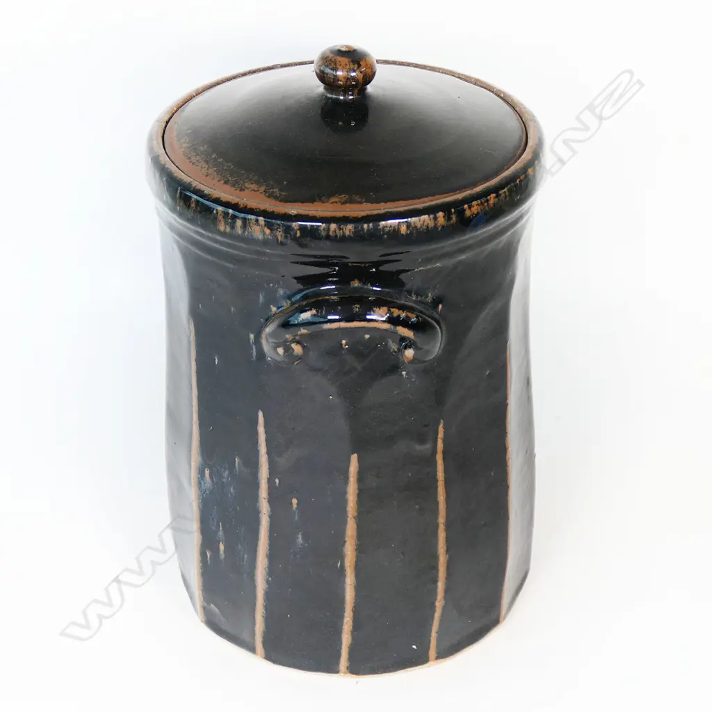 Peter Alger (Northland) tenmoku glazed large lidded storage vessel. Facet cut body with lug handles. The very well executed black tenmoku showing red/brown at the ridges. Impressed mark. H.365mm Image 1++