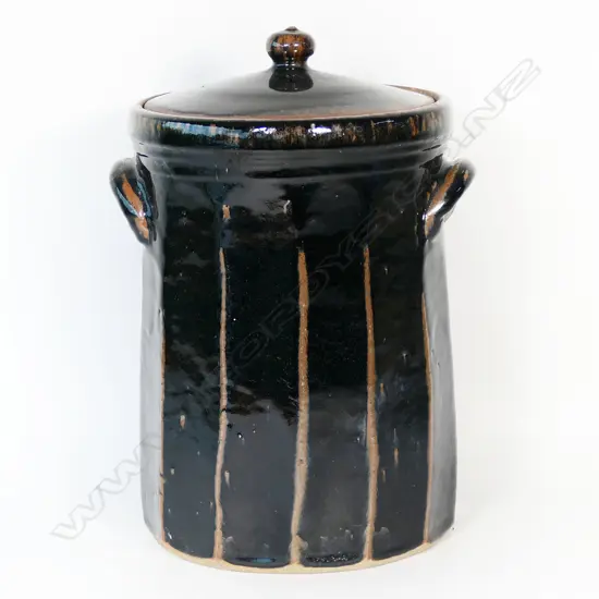 Peter Alger (Northland) tenmoku glazed large lidded storage vessel. Facet cut body with lug handles. The very well executed black tenmoku showing red/brown at the ridges. Impressed mark. H.365mm