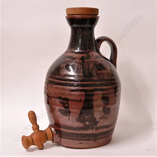 Crewenna Pottery (1962-1972 Harry & May Davis) flagon with dark tenmoku glaze - stylised decoration in lustrous dark red/brown tones, turned wooden topped cork stopper and tap. Potter's mark to base of strap handle. H.320mm.