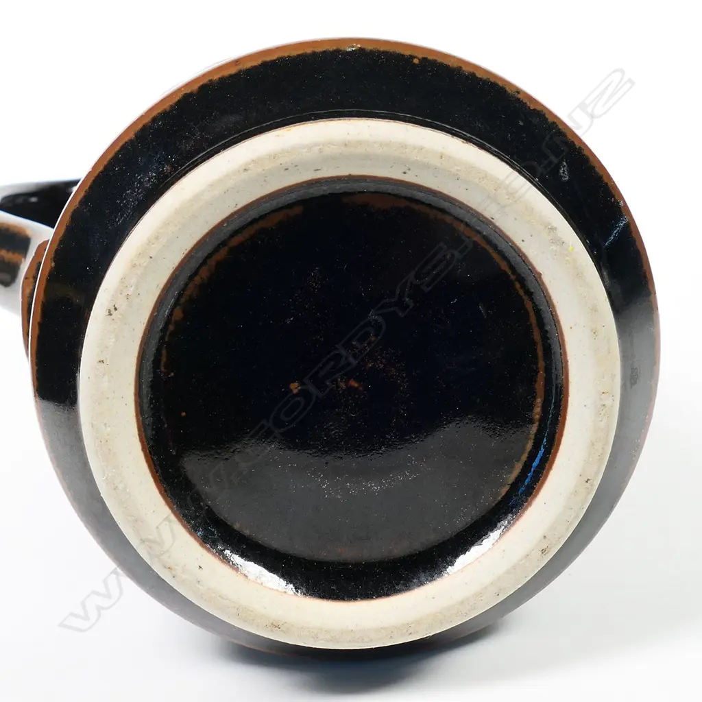 Peter Holmes tall cylinder jug with blossom decoration in brown and pink over lustrous tenmoku glaze. The jug reflects potter's interest in Japanese ceramics. Stamped mark at handle base. H.270mm Image 1++