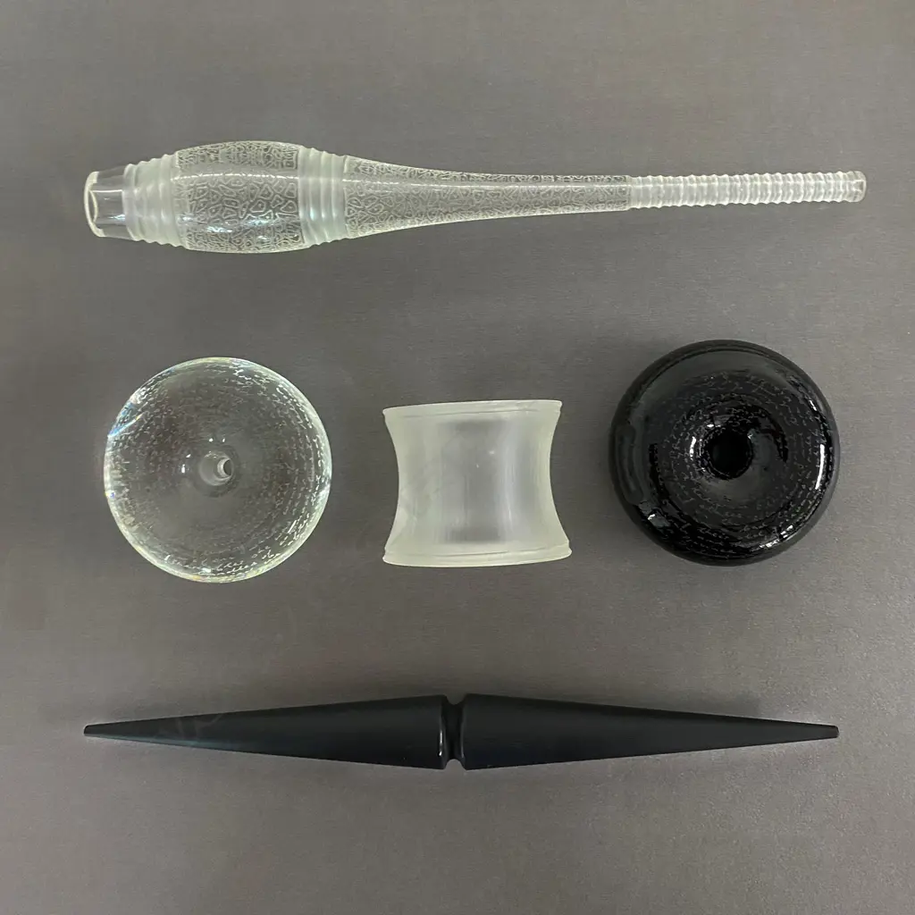 Lyndsay Patterson Glass five piece 'Token' set 'Never Been Touched' - c.2009, the mouth blown and engraved clear and black glass pieces of stylised pacific artefact forms, Pūtōrino (flute), Pōtaka tā (whip top), Mau kakī (reel necklace unit) and two māhē (sinker forms), Image 1++