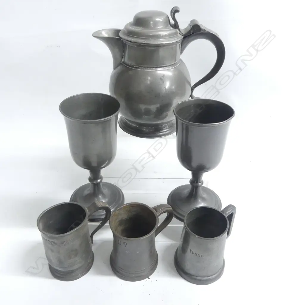 An English pewter bulbous bodied lidded ale measure with volute thumb piece to the domed cover H.200mm;  a pair of James Dixon & Sons pewter goblets with bell form bowls H.185mm and three pewter tankards Image 1++
