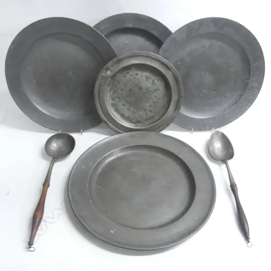 A large Georgian period pewter charger. Dia.420mm; three Georgian chargers.  Dia.380mm; a large Georgian plate. Dia.300mm- and two European pewter serving spoons with turned wooden handles,