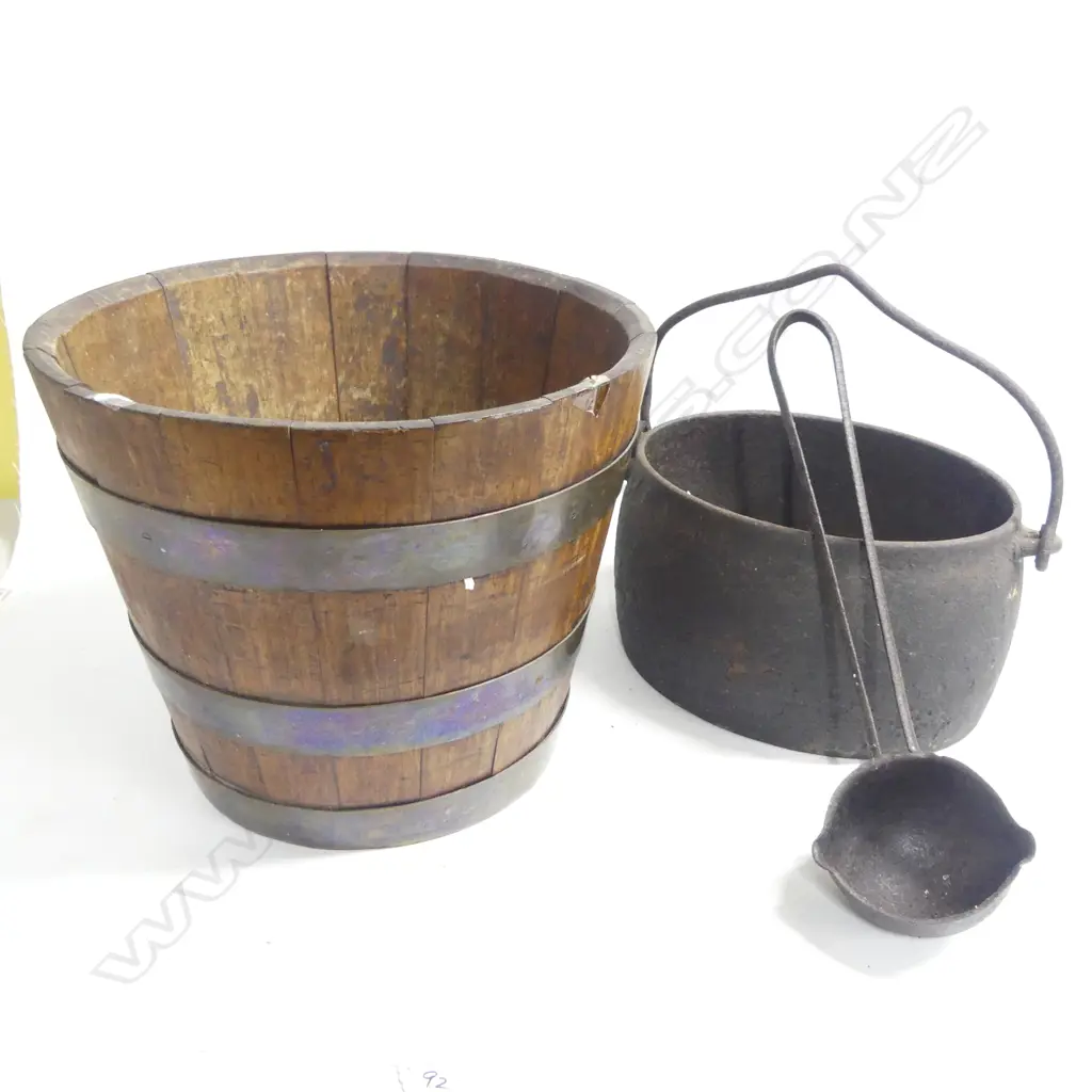 A coopered oak bucket, the tapering staves bound by three brass rings. H.305mm; along with a cast iron oval pot and ladle Image 1++
