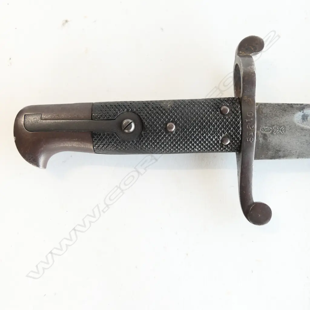 British P.1856/58 Sword Bayonet. Good leather grips. Bar on barrel fitting. Cross guard numbered ‘01258’. Yataghan blade edge with some old file marks and a small amount of old pitting at the tip. Leather scabbard with old dent by chape and chape tip holed Image 1++