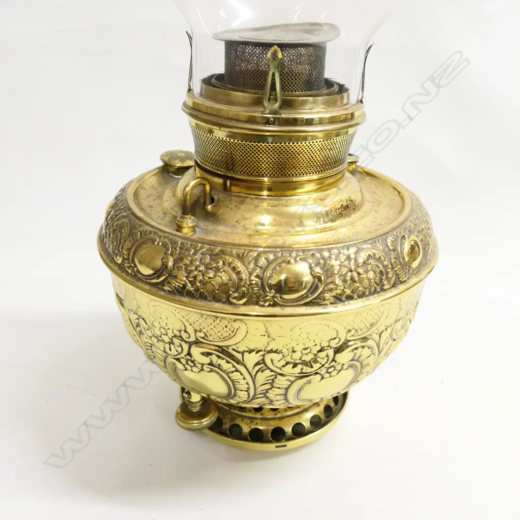 A Miller's brass paraffin lamp, with a large heavily embossed brass oil reservoir, with glass chimney. H.560mm. Image 1++