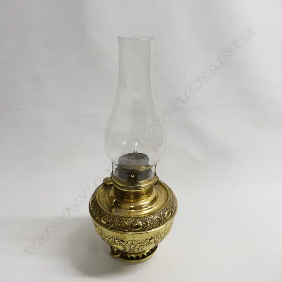 A Miller's brass paraffin lamp, with a large heavily embossed brass oil reservoir, with glass chimney. H.560mm.