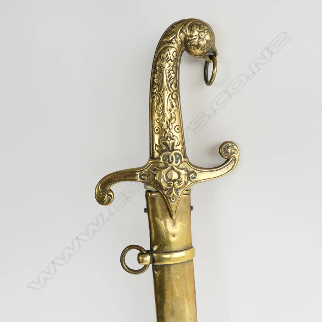 British Mamaluke-stle Army Band sword, with cast brass grip, recurved crossguard with langets, pommel with foliate raised decoration, and ring for sword knot. 710mm curved, single edged blade with scattered light to moderate pitting. Image 1++