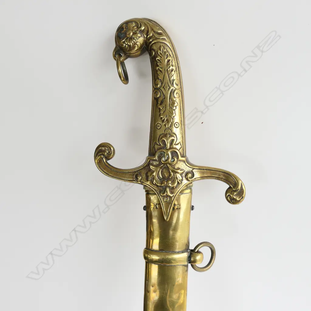 British Mamaluke-stle Army Band sword, with cast brass grip, recurved crossguard with langets, pommel with foliate raised decoration, and ring for sword knot. 710mm curved, single edged blade with scattered light to moderate pitting. Image 1++