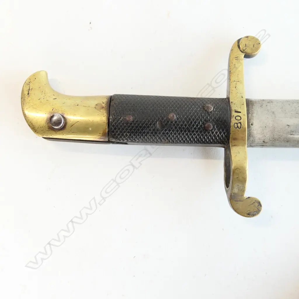 Lancaster Pattern 1855 bayonet with leather scabbard. Made for the Lancaster Carbine Rifle, pipe back spear pointed blade with even stained patina, leather grips and brass hilt, and crossguard numbered 108, brass mounted black leather scabbard with one crease. Image 1++