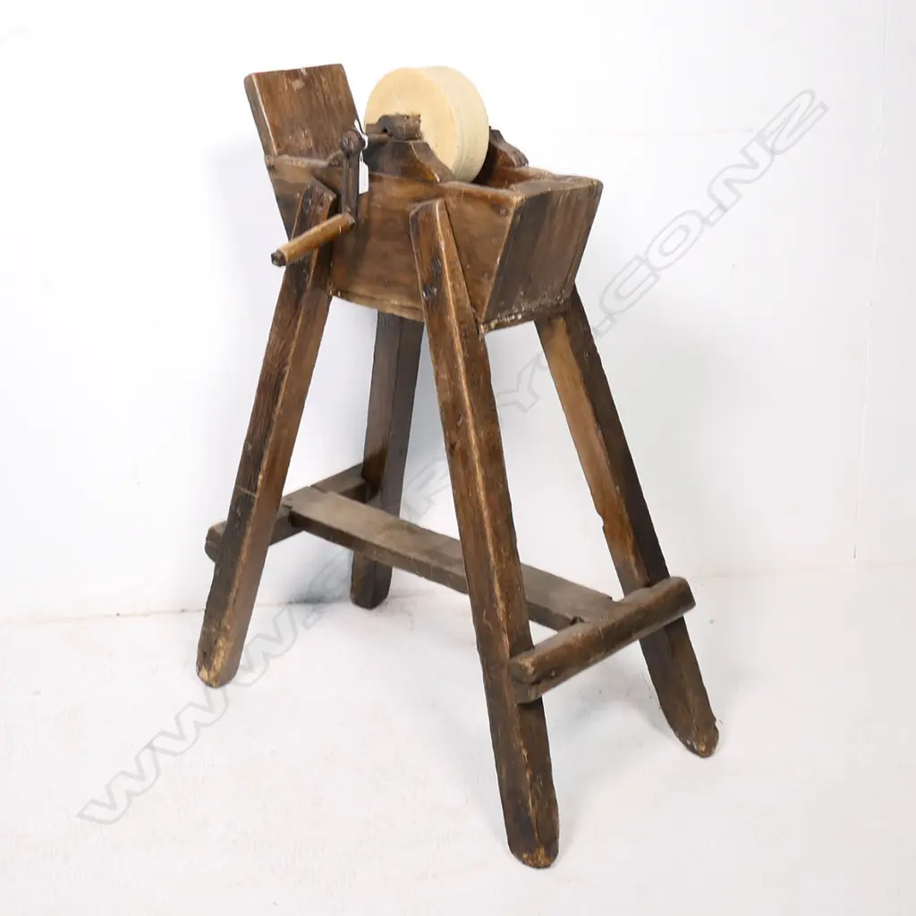 A 19thC blade sharpening grindstone wheel supported on a fruitwood trough frame, raised on four legs with a stretcher base.  720 x 380 x 900mm Image 1++