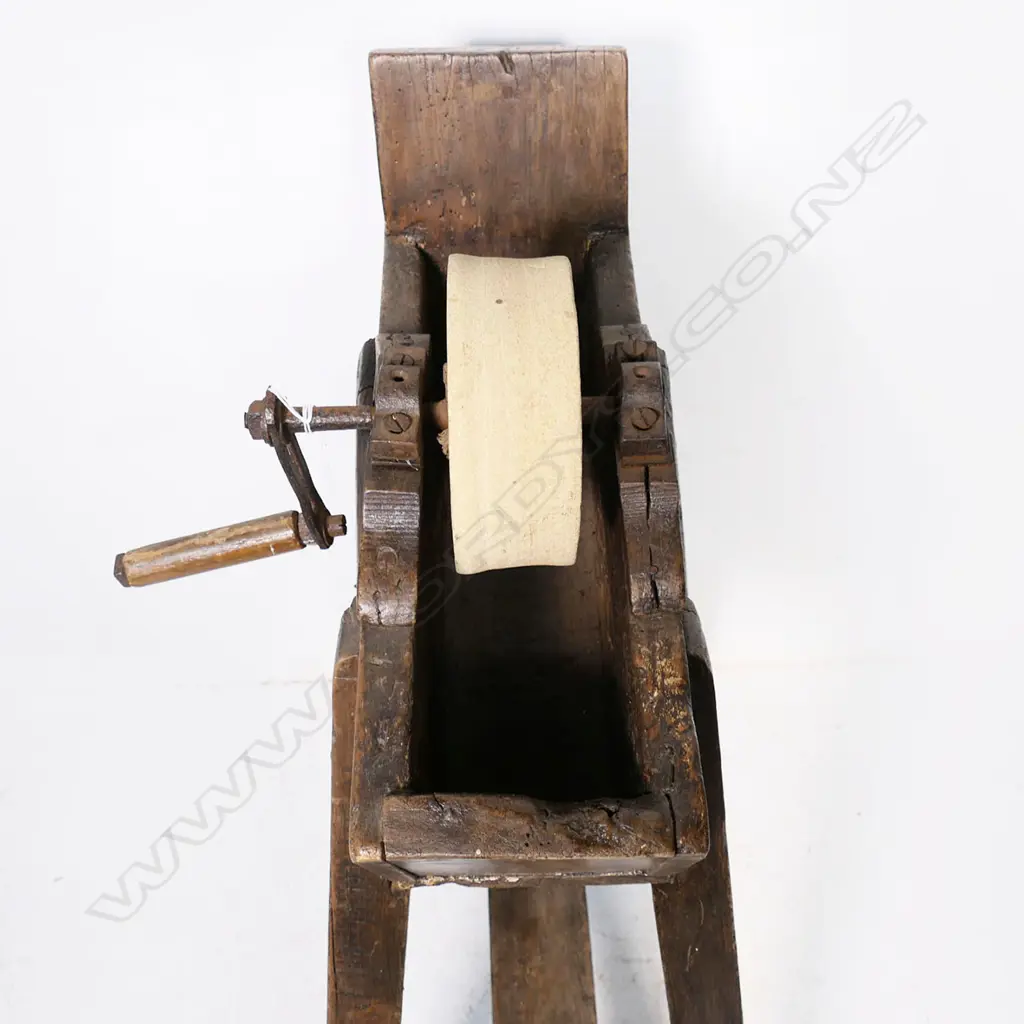 A 19thC blade sharpening grindstone wheel supported on a fruitwood trough frame, raised on four legs with a stretcher base.  720 x 380 x 900mm Image 1++
