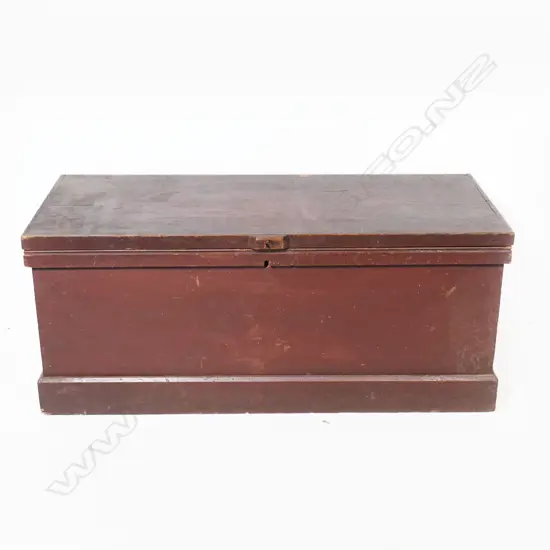 A red painted pine footlocker, with steel carry handles, plinth based. 880 x 380 x 370mm.