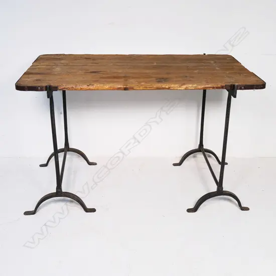 A mid-19thC wrought iron and pine military campaign table, the plank top with iron strapped corners, raised on two stirrup based wrought iron legs. 1230 x 7870 x 770mm