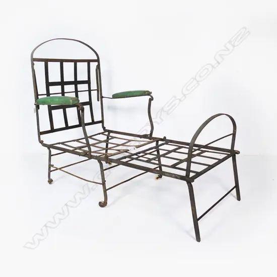 A wrought iron folding chair, on porcelain castors and later green padded arm rests