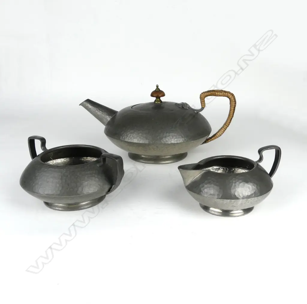A three-piece hand beaten Tudric pewter tea set made for Liberty & Co. Image 1++