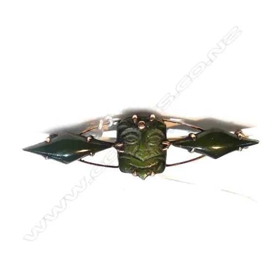 9ct GOLD & GREENSTONE BROOCH - CARVED WITH A MASK FLANKED BY LOZENGES. TOTAL 3.2gm