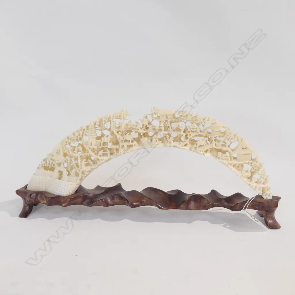 A CHINESE CARVED HIPPOPOTAMUS TUSK ON A ROSEWOOD STAND. W.320mm. Image 1++