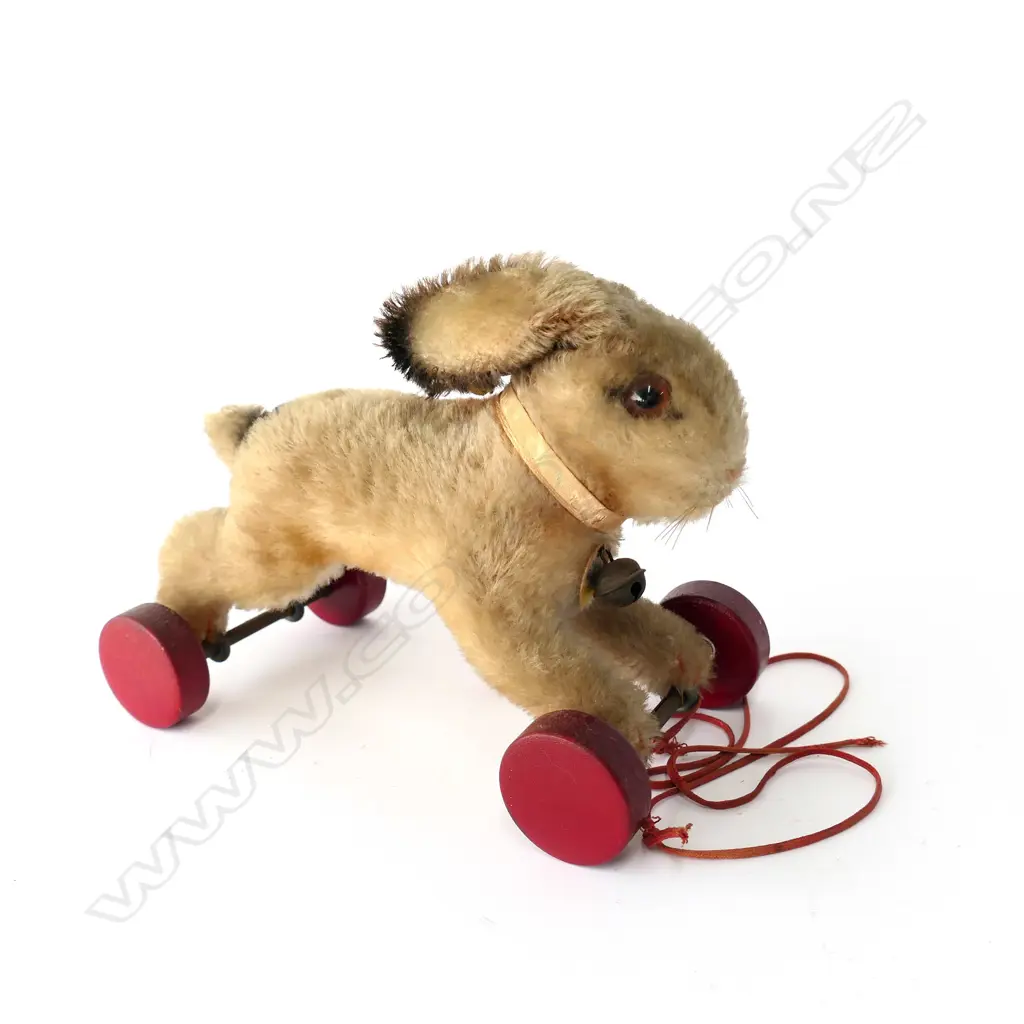 1314. With light tan wool plush; brown and black plastic eyes; red painted wooden wheels; button and tag in ear and paper label to bell. Image 1++