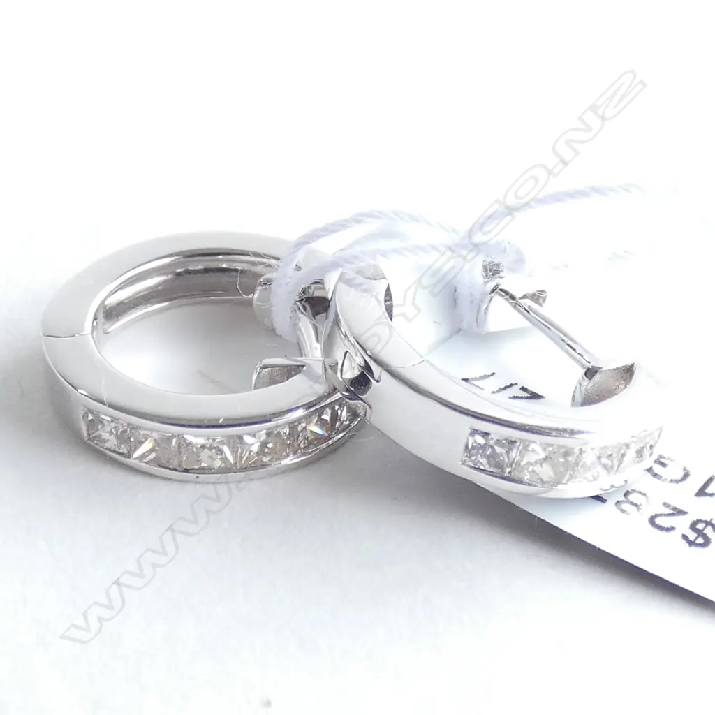 A pair of 18ct white gold and diamond huggie earrings, each channel set to the front with six princess cut diamonds, plain polished backs, notched post fittings. Tdw. 0.62ct. Valuation available. Image 1++