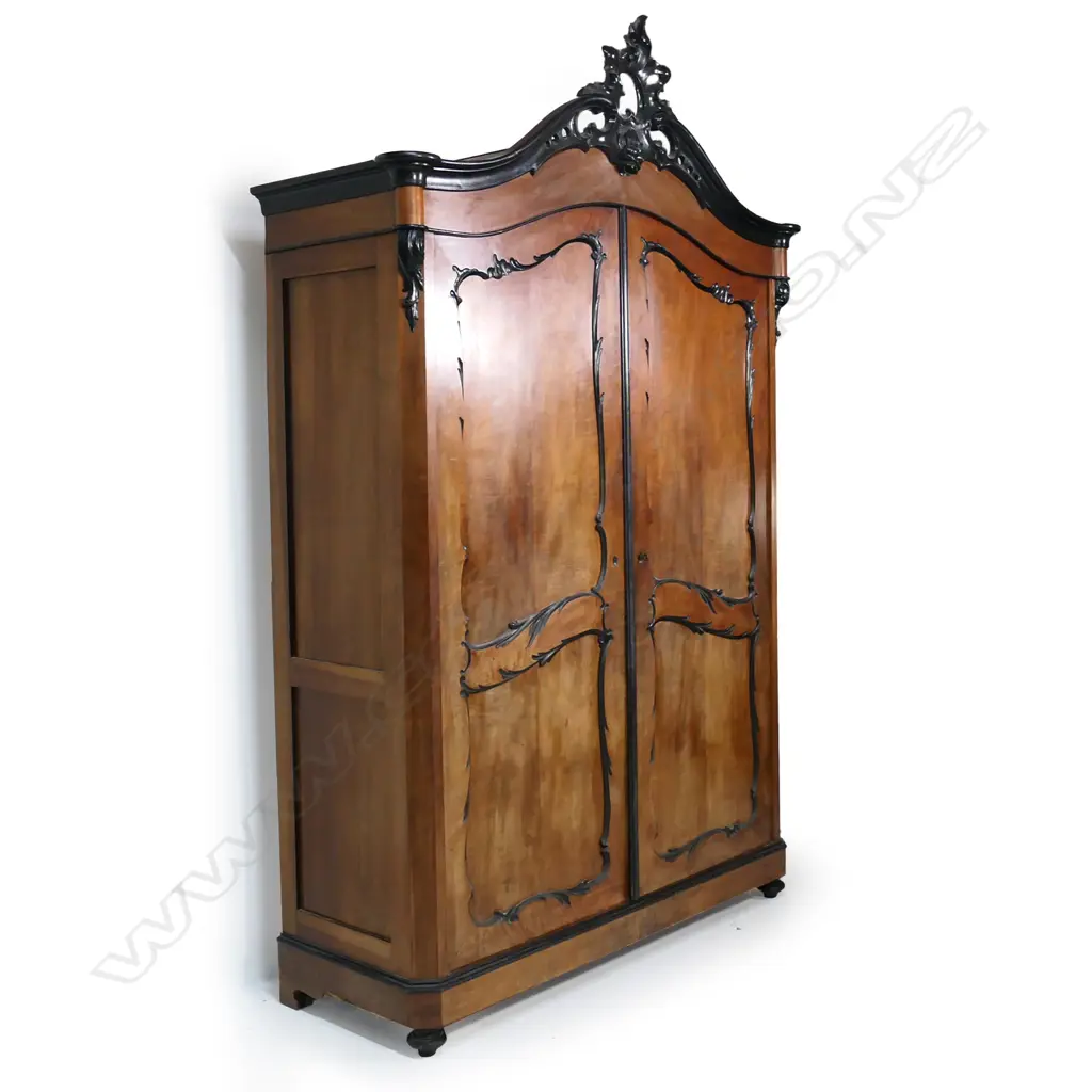 A large 19thC walnut armoire; the pair of double panelled doors with ebonised scroll detail, enclosing two drawers to the base; the arched top with classic French carved, pierced and ebonised pediment; panelled sides. 1580 x 630 x 2500mm. Image 1++