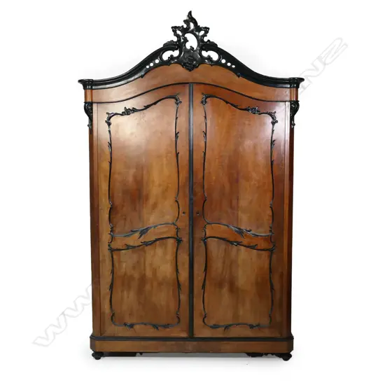 A large 19thC walnut armoire; the pair of double panelled doors with ebonised scroll detail, enclosing two drawers to the base; the arched top with classic French carved, pierced and ebonised pediment; panelled sides. 1580 x 630 x 2500mm.