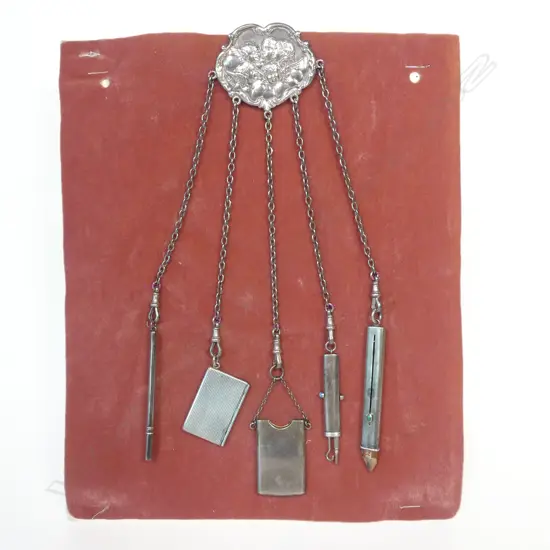 An Art Nouveau Angel's Heads sterling silver chatelaine with five suspended accoutrements, Birmingham 1900 by Henry Williamson Ltd.,