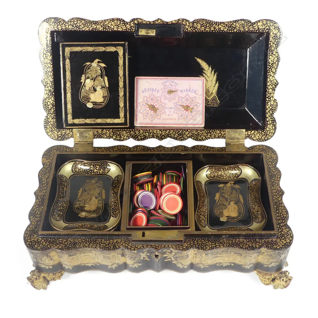 A Chinese export lacquer game box, early 19thC, on gilt wood dragon head legs with serpentine sides, rounded corners and hinged top, overall chinoiserie decoration in various shades of gold, the top considerably worn. Image 1++