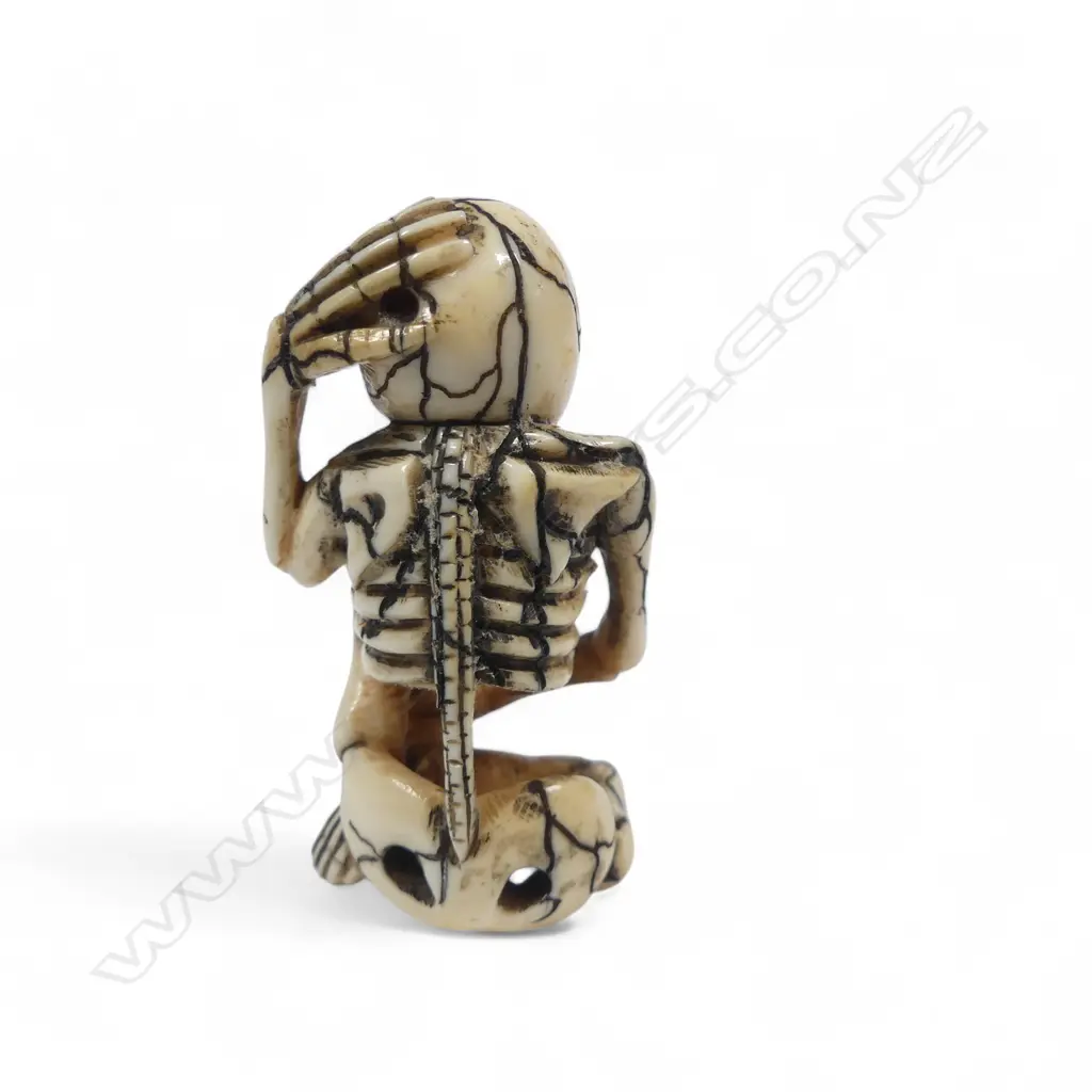 Japanese ivory netsuke of a skeleton, humorously rendered sitting cross-legged with one hand to his skull the other clasping his ankle,  signed to the foot 'Matsuyama'. H.55mm Image 1++