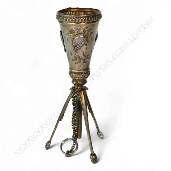 An uncommon unmarked silver posy holder, possibly French, conical with three applied classical busts, raised on three leaf spring activated folding legs.