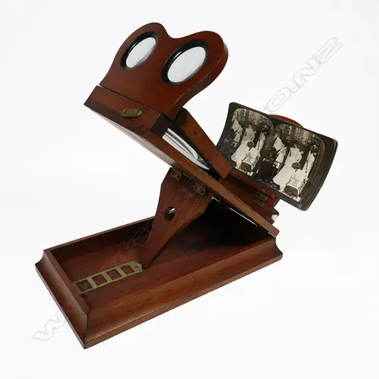 A folding tabletop magnifying stereoscopic photograph and cartes de visite viewer, mahogany case with 3¾" lens and removable binocular lenses, folds to 145 x 270 x 75mm.