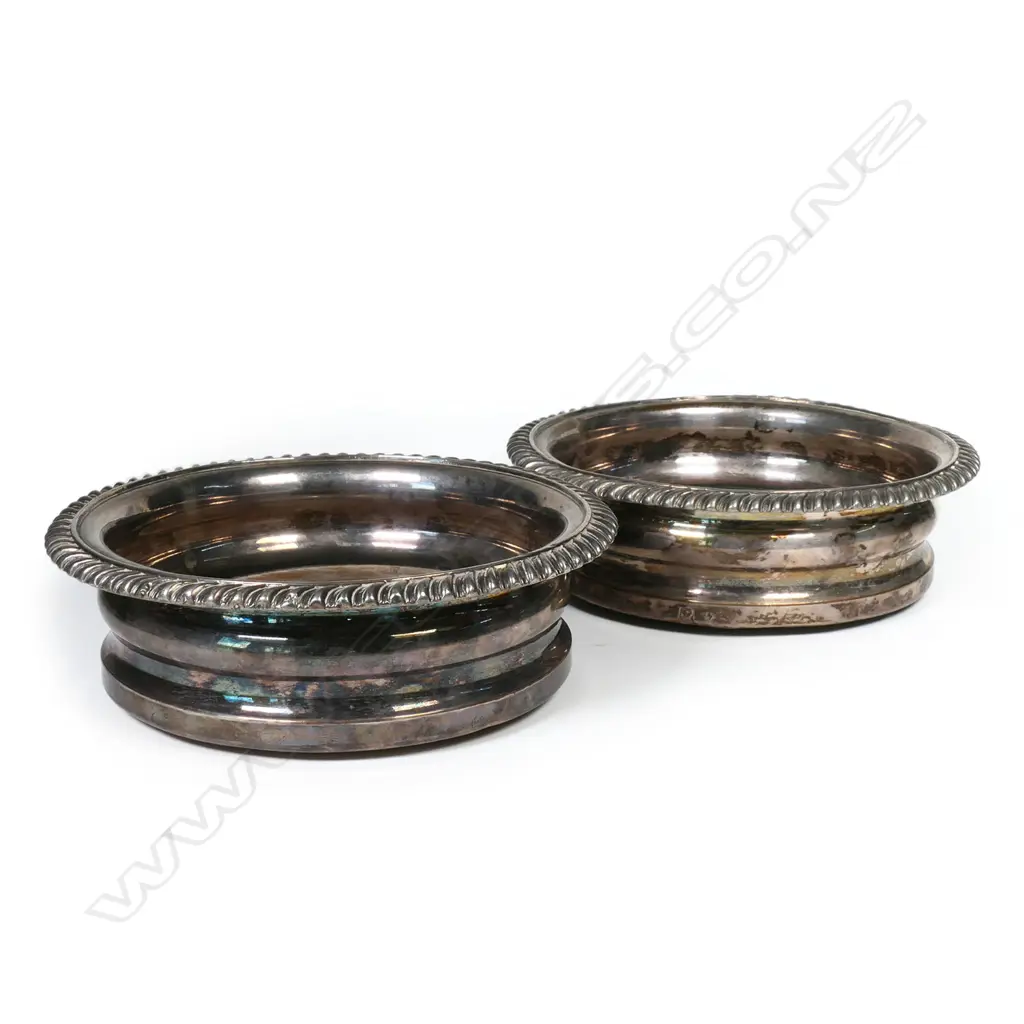 A pair of early silver plate wine coasters with swollen sides, floral decoration to rim and wooden inset bases. Dia.160mm. Image 1++