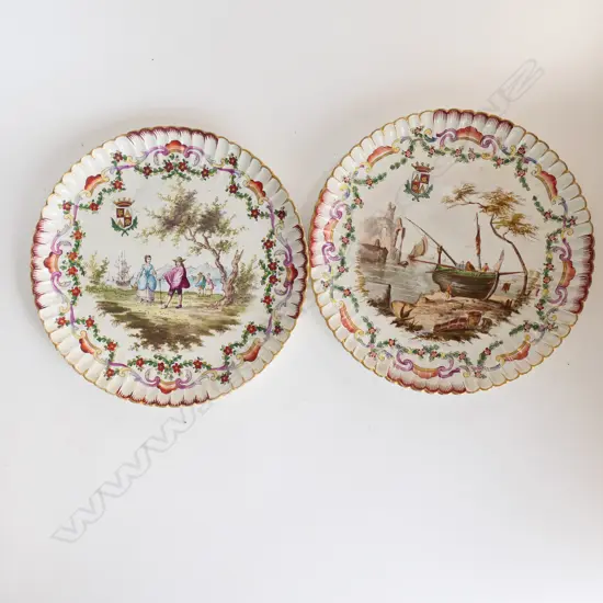 A pair of French porcelain circular armorial shallow dishes with polychrome transfer decoration of figures and coastal scenes