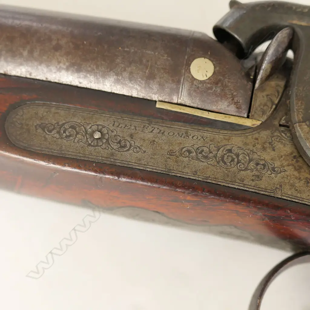 12g Double Barrel Percussion Shotgun by Alex Thompson, Edinburgh. 30" barrels. Metal with good Damascus pattern. Action strong, LH hammer a replacement. Lock with light engraving, steel butt plate and trigger guard with engraving. Wood in good tidy condition with chequering to wrist. Provenance: NZAHAA, 12/07/2014, Lot 1073, $760. *NO LICENCE REQUIRED Image 1++