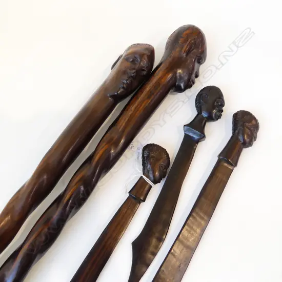 FIVE CARVED ZEBRAWOOD ITEMS. TWO BARLEy TWIST WALKING STICKS L.940mm & THREE LETTER OPENERS ALL WITH MALE HEAD FINIALS.