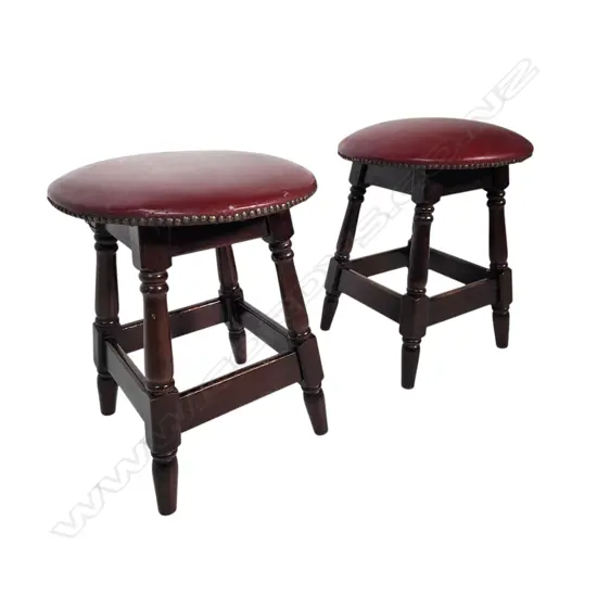 HEAVY PAIR OF VINTAGE WOODEN STOOLS – DARK WOOD WITH RED UPHOLSTERED SEATS AND NAILHEAD TRIM.