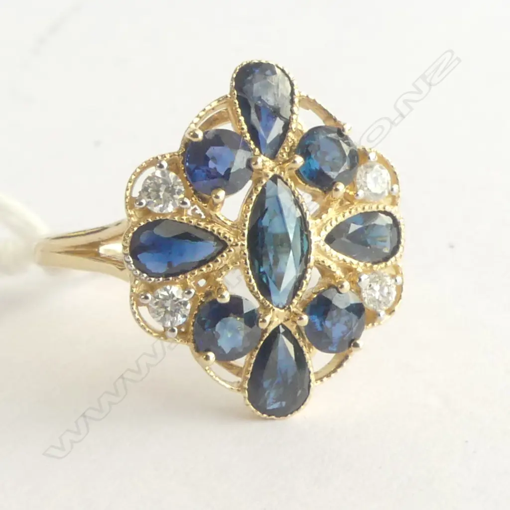 A 14ct gold sapphire and diamond Art Deco style ring a central marquis cut sapphire to the centre of four tear drop cut and four round cut sapphires (slight inclusions/one broken) set to a filigree mount together with four round cut diamonds (Colour H-I, Clarity SI2-I2) micro claw set. TSW. 2.08ct. TDW. 0.14ct. Ring size P. Image 1++