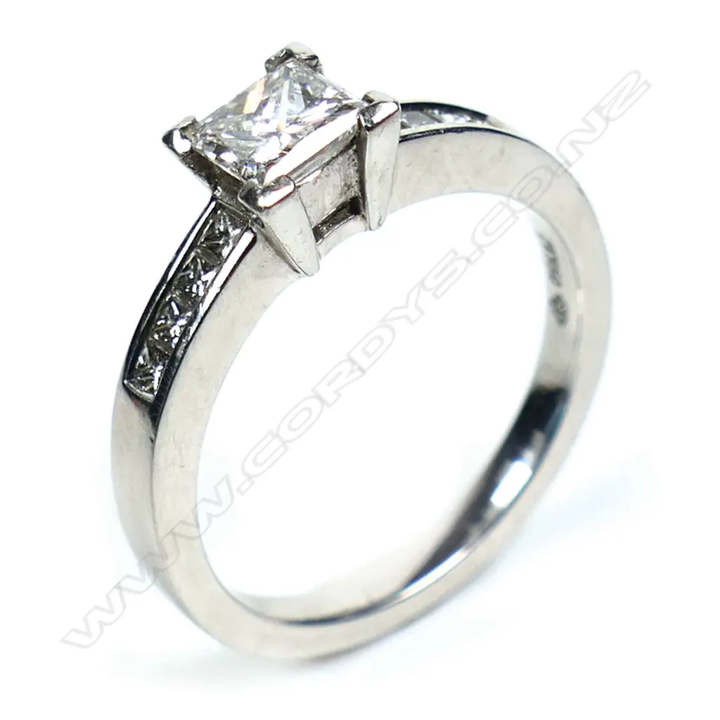 A platinum and diamond ring with a 0.50ct princess cut diamond channel set, with a further four small princess cut diamonds set to each shoulder. TDW. 0.80ct. Size M. Image 1++