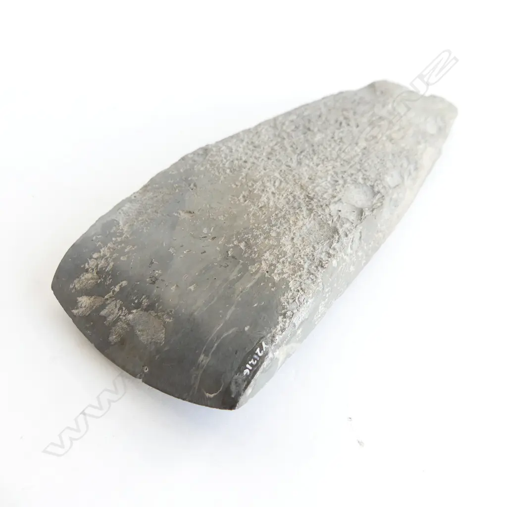 A Māori pre-European stone toki of large wide tapered form and grey tone, flaked at pole, fine all over pecking, the smooth polished curved blade with sharp edge. L.200mm Registered Y21216. Note: Buyer must be registered to purchase. Image 1++