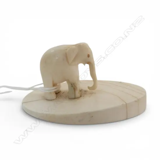 OLD SMALL CARVED IVORY ELEPHANT on oval slab section ivory base. L.63mm nicely polished. Tusks absent