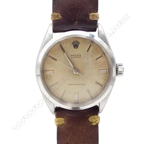 A 1950's Rolex Oyster 6144 gent's wristwatch  mid size 33mm diameter stainless steel case wind down Rolex crown. baton markers, the cream toned dial named and with 'Oyster' and 'Shock-Resisting'. Working. Later old brown leather strap with Rolex branded clasp.