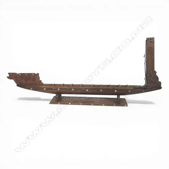 A large mid/late 20thC Māori carved wood model waka on carved stand,