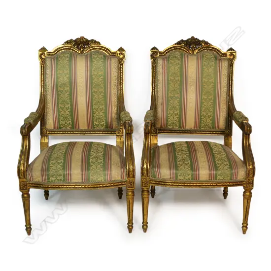 A pair of French style open elbow armchairs the gilded frames with carved decoration upholstered in a stripped patterned fabric. The back of both chairs require reupholstering. 570x 570 x 1050mm.
