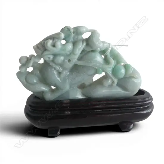 CHINESE PALE GREEN JADE CARVING OF A KYLIN & SCROLLING FORMS. L.130mm. ON WOOD STAND
