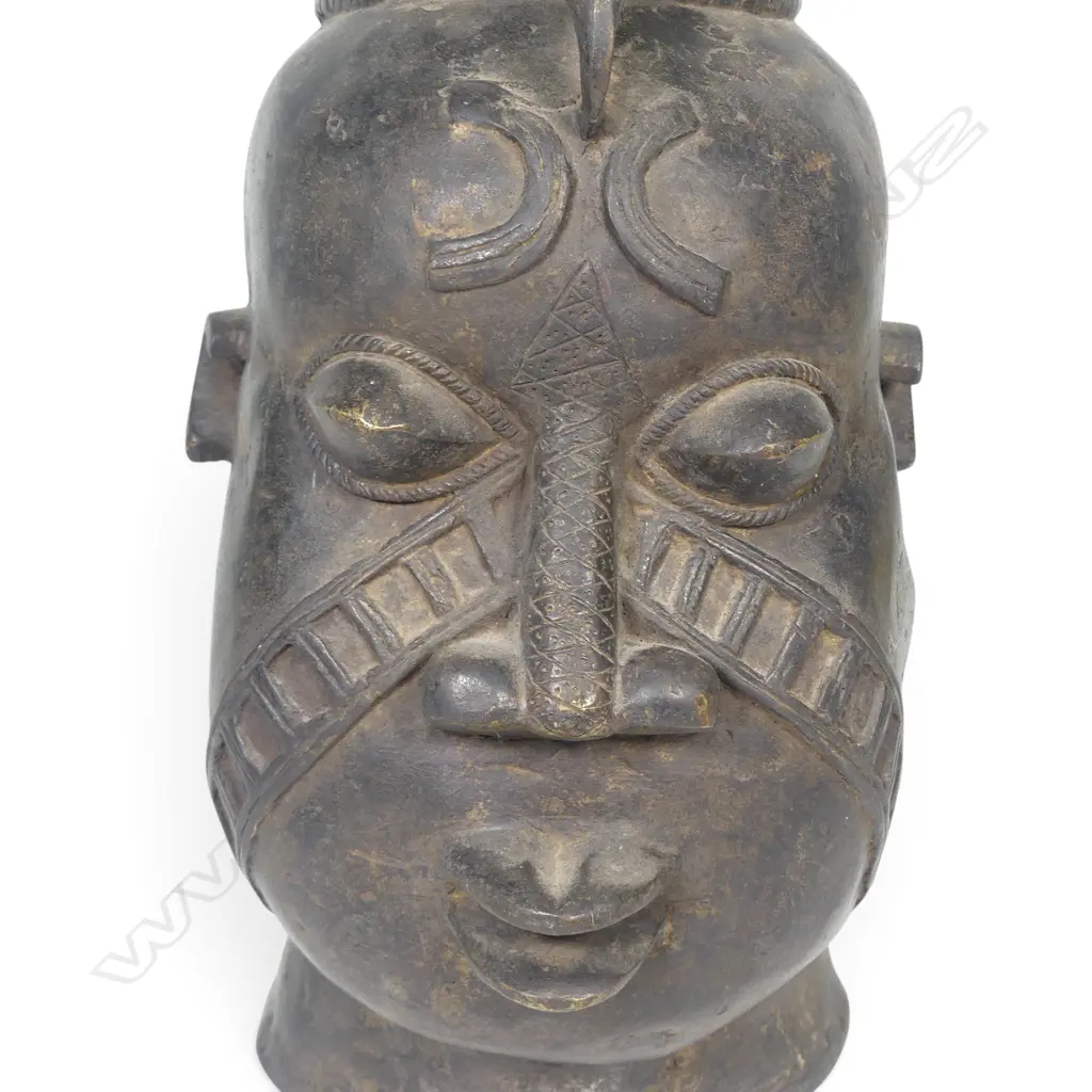 WEST AFRICAN STYLIZED DARK BRONZED METAL HEAD WITH GEOMETRIC FACIAL MARKINGS & PROMINENTS EYES,DENT ON LEFT SIDE.H.333MM Image 1++