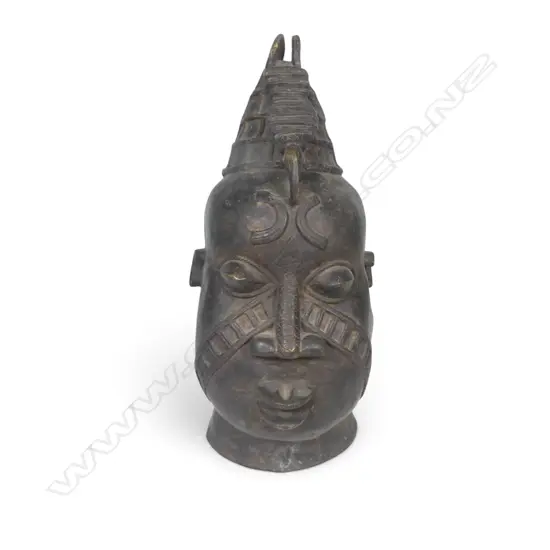 WEST AFRICAN STYLIZED DARK BRONZED METAL HEAD WITH GEOMETRIC FACIAL MARKINGS & PROMINENTS EYES,DENT ON LEFT SIDE.H.333MM