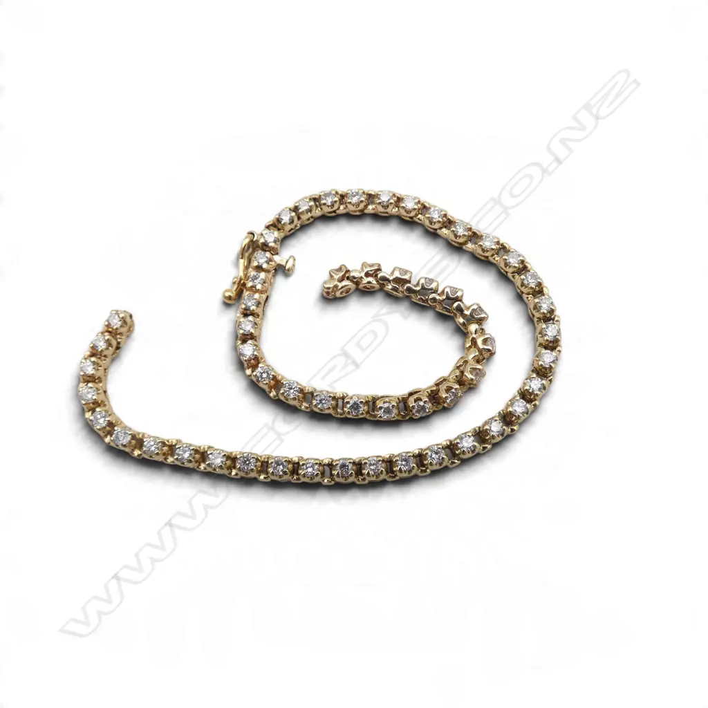 A 9ct gold and diamond tennis bracelet with fifty-five small round brilliant cut diamonds (Colour F-G, Clarity SI2) claw set - push clasp with safety catch. TDW. 1.80ct. 9.60gms. L.200mm. Faults to bracelet LINK DAMAGED AND NEEDS REPAIRING Image 1++
