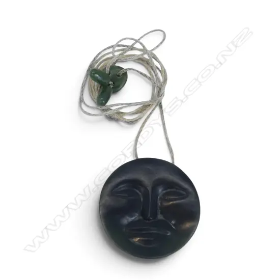 POUNAMU CIRCULAR MOON FACE CARVED PENDANT. Dia.43mm. Hidden suspension holes to back. On plaited cord