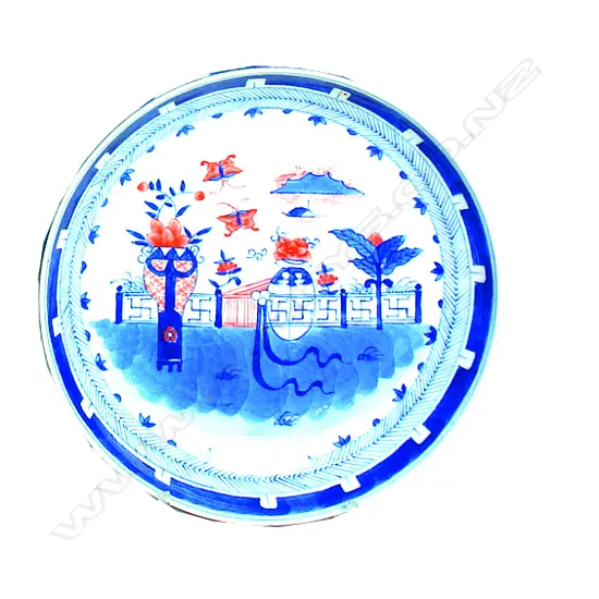 A Chinese porcelain dish painted with a wall garden in underglaze blue and iron-red within a chevron border