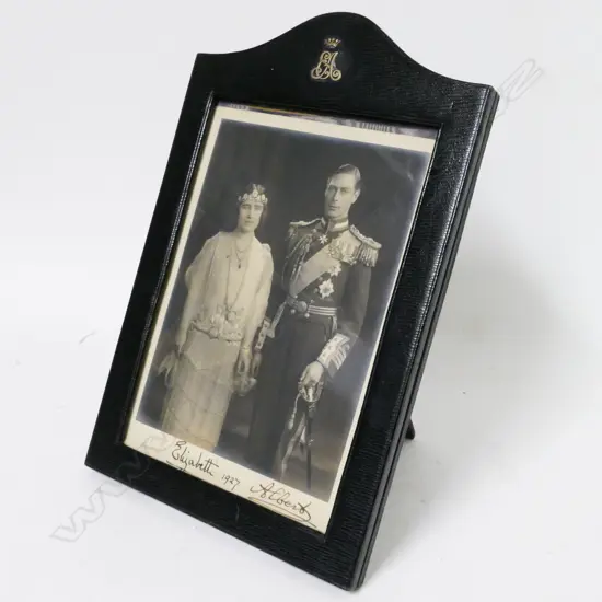A vintage leather photo frame holding a signed photograph of King George VI and Queen Elizabeth II
